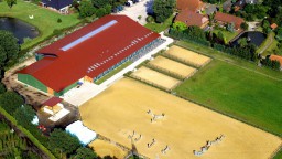Luftaufnahme eines großen Reit- und Stallkomplexes mit Trainingsgelände und ländlicher Umgebung.
