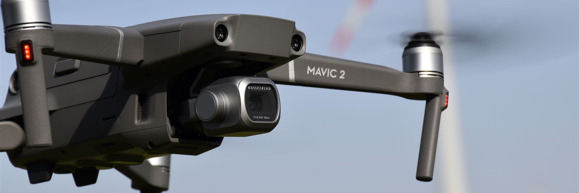 Eine DJI Mavic 2 Drohne fliegt in der Luft vor einem hellen Hintergrund.